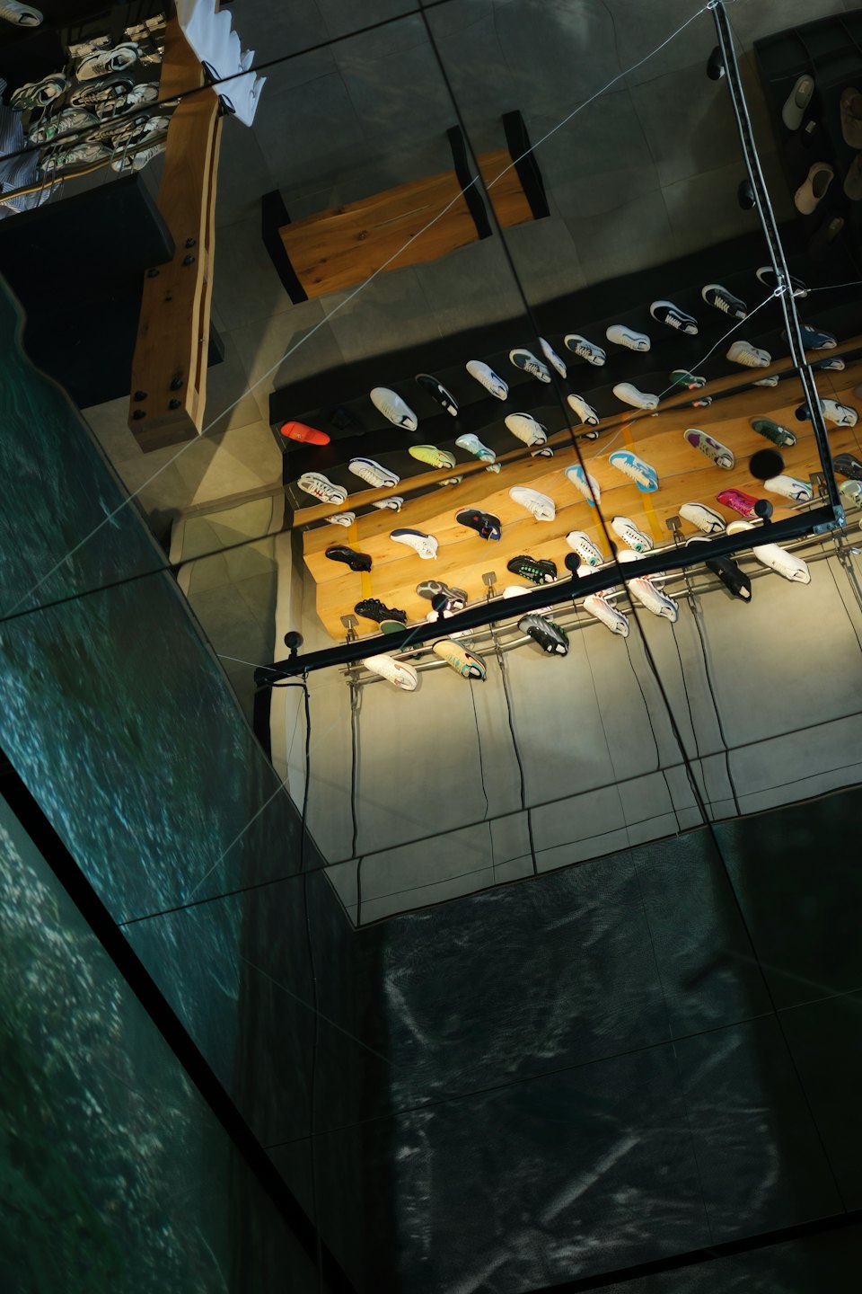Sneakers displayed on wooden shelves inside a modern shoe store.
