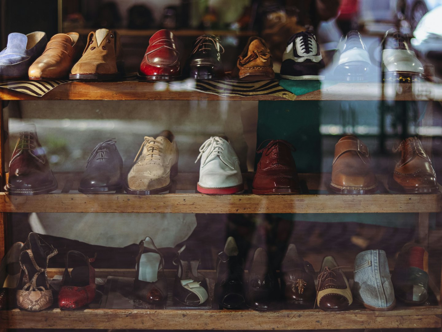Various leather and suede shoes displayed on rustic wooden shelves.
